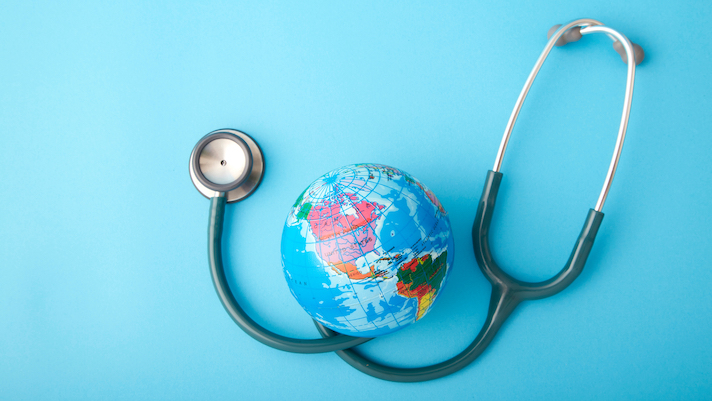 Close-Up Of Stethoscope With Globe Over Blue Background